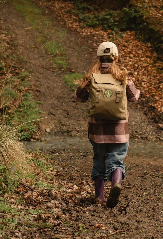 Person with a backpack walking on a leaf-covered path in a forest