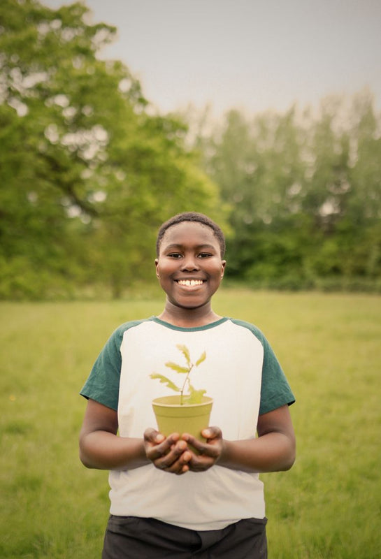 Person holding a potted plant in a grassy field