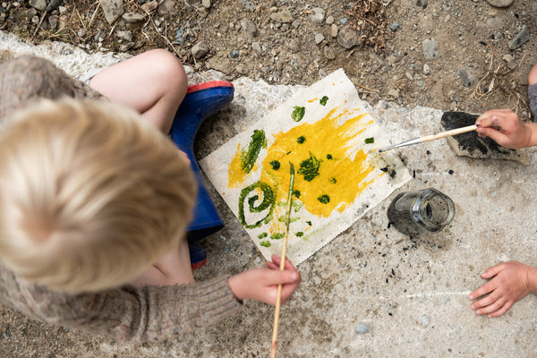 child painting a flag with paintbrushes and natural paints