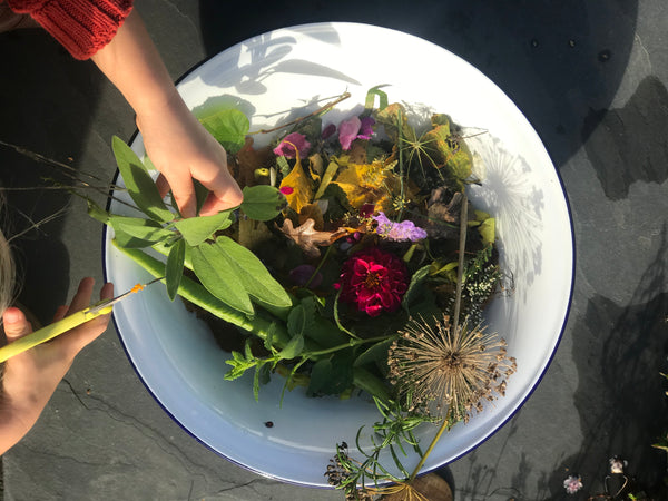child uses scissors to snip natural foliage, herbs and flowers to make nature confetti