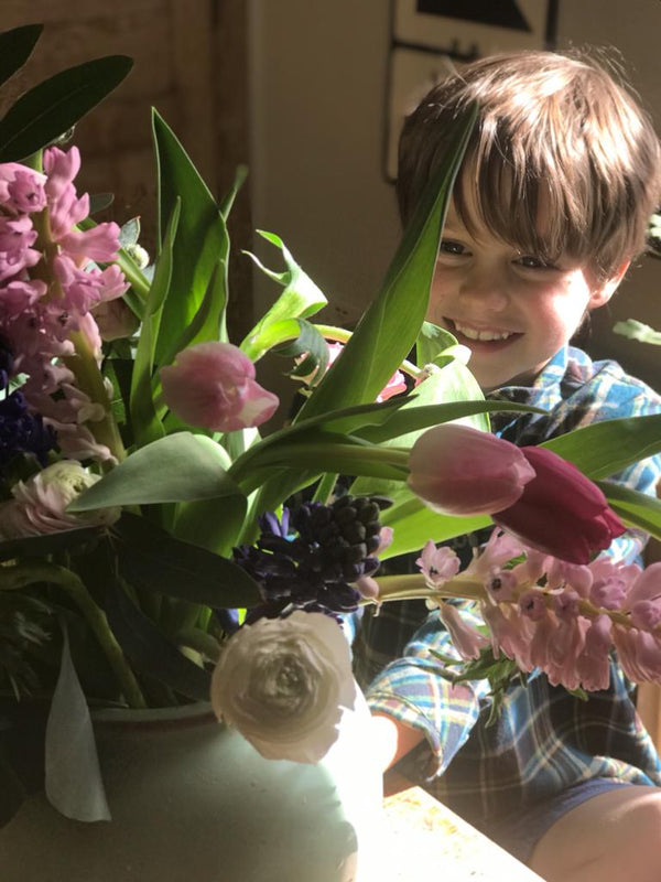 Child arranges spring flowers - daffodils, tulips, hyacinth