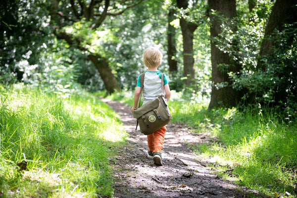 A child with a den kit walks into the woods to play with dens & nature