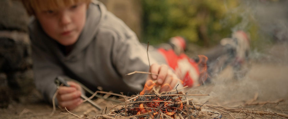 child putting sticks onto a small fire