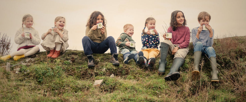 Children sitting on a grassy hill with a neutral background
