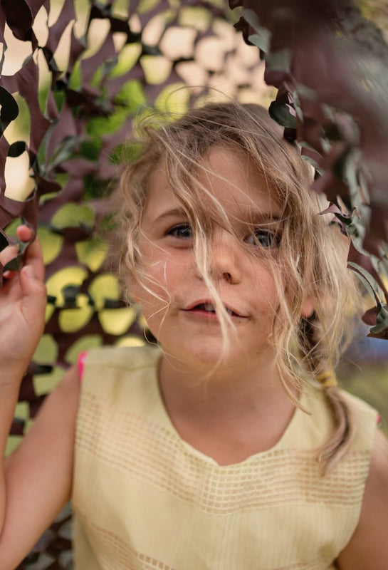 child underneath camouflage netting