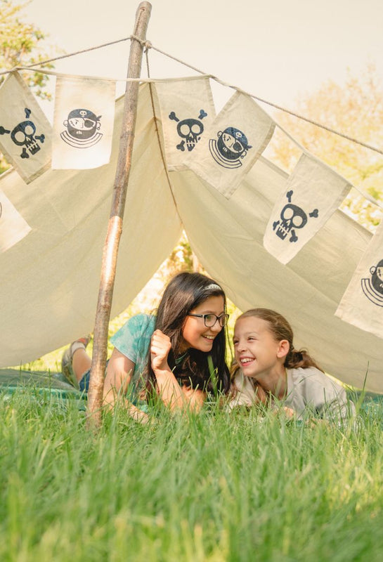 two children underneath a pirate themed den held up by den poles